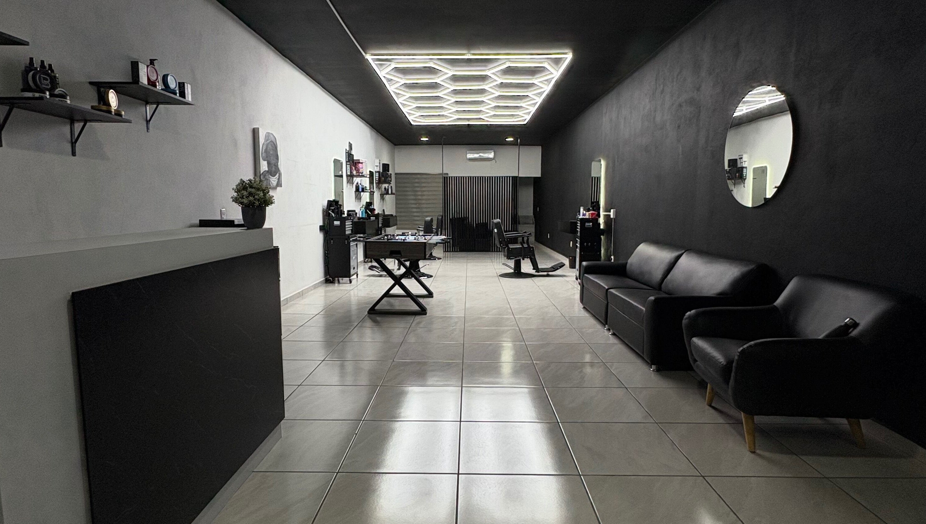 Interior moderno de Fonsek Barber en Tepic, Nayarit, MX con sillas de cuero y espejo redondo.