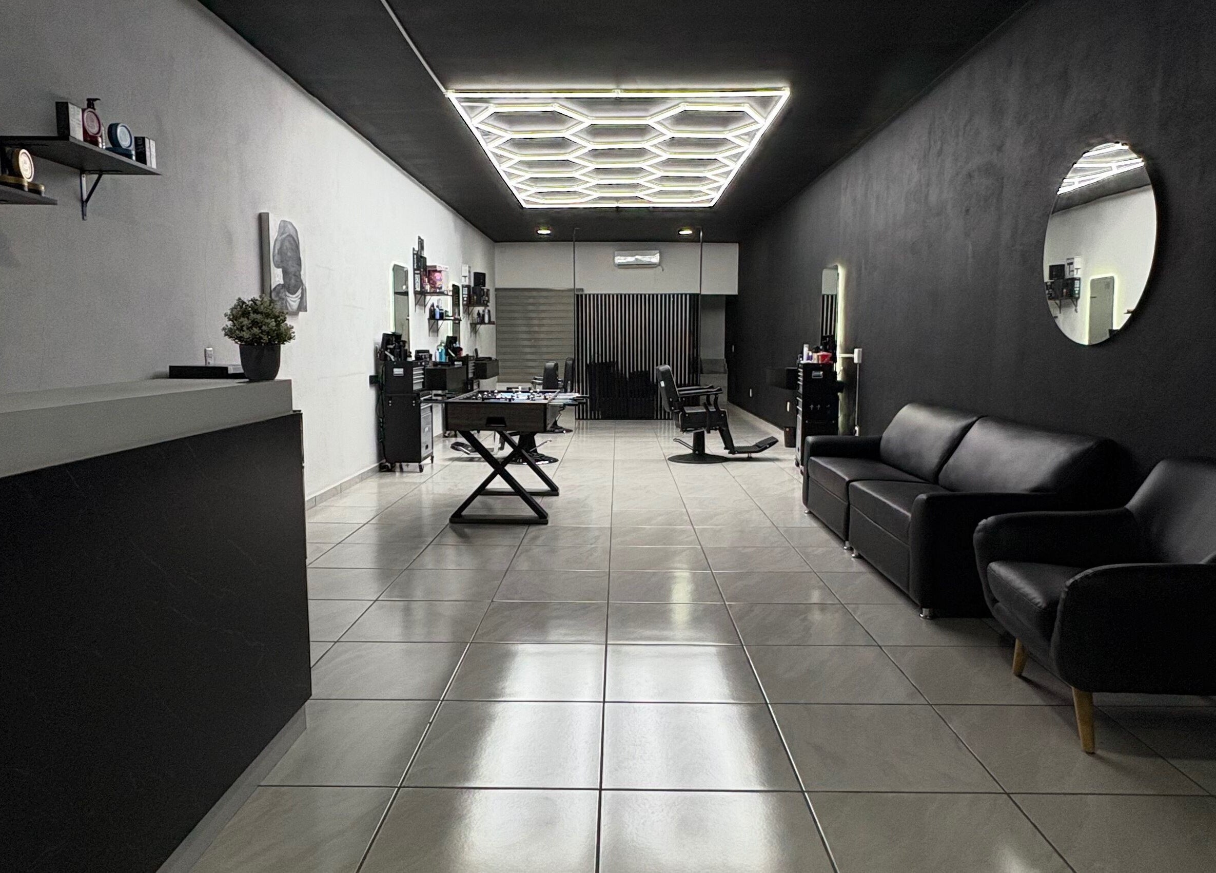 Interior moderno de Fonsek Barber en Tepic, Nayarit, MX con sillas de cuero y espejo redondo.