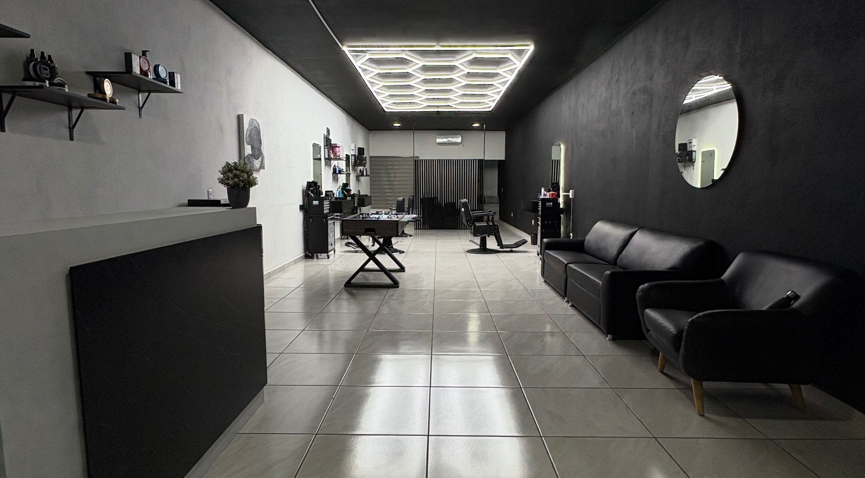 Interior moderno de Fonsek Barber en Tepic, Nayarit, MX con sillas de cuero y espejo redondo.