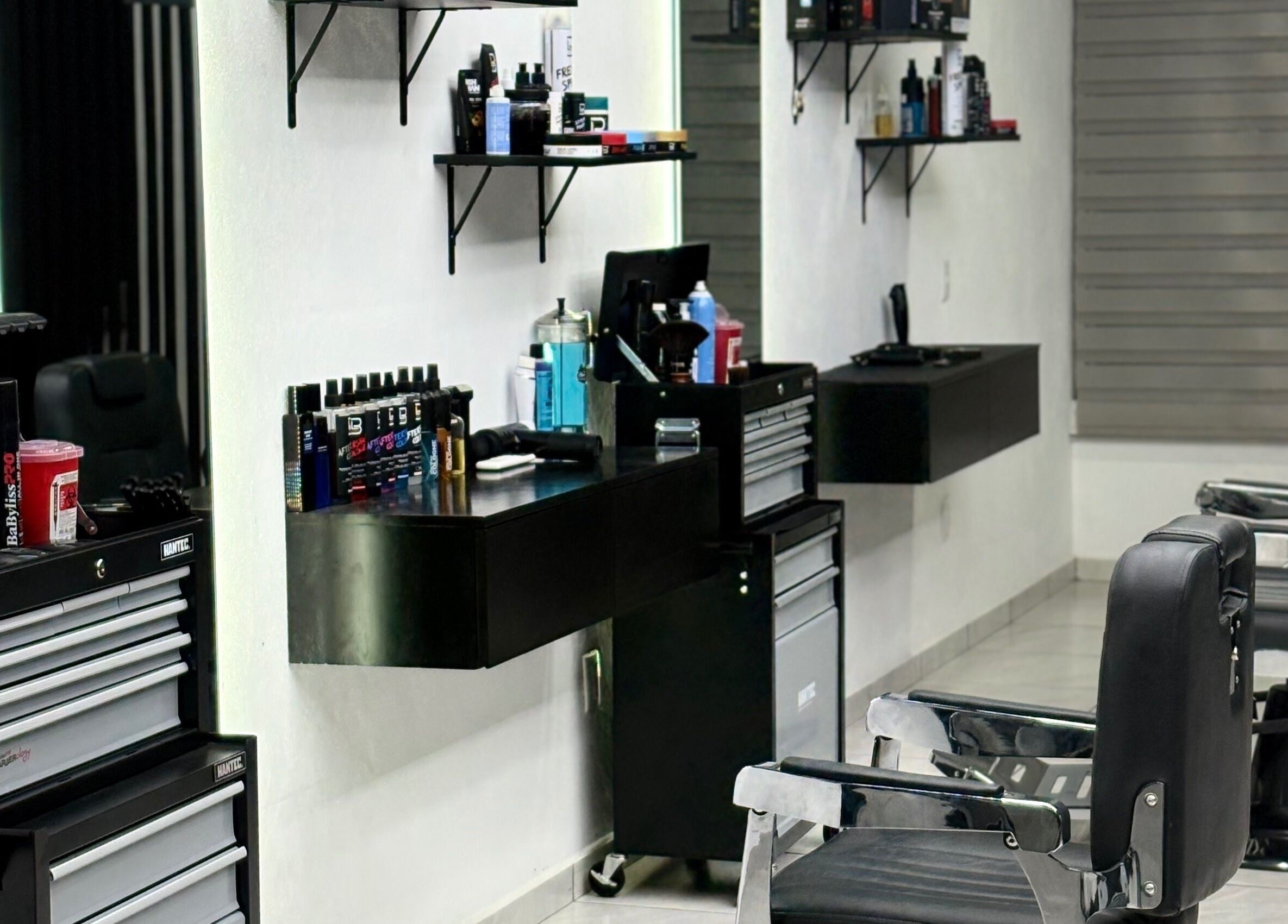 Interior moderno de Fonsek Barber en Tepic, Nayarit, MX, mostrando sillas de barbero y productos en estantes.