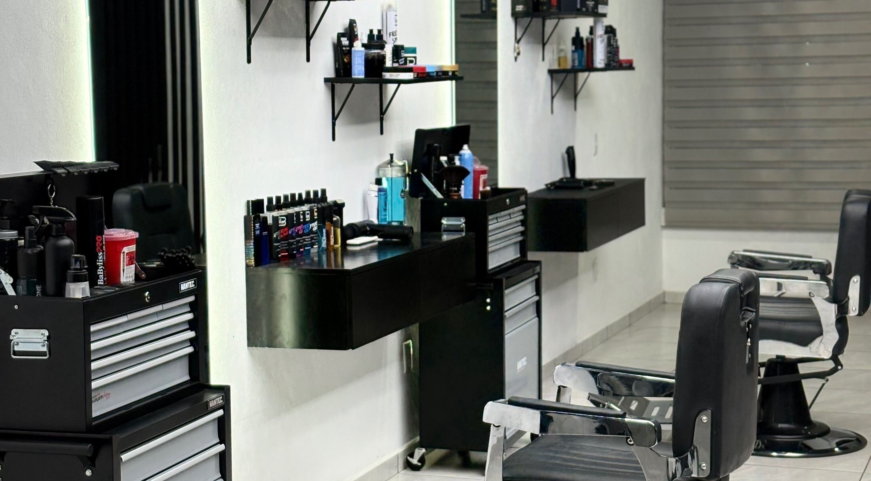 Interior moderno de Fonsek Barber en Tepic, Nayarit, MX, mostrando sillas de barbero y productos en estantes.