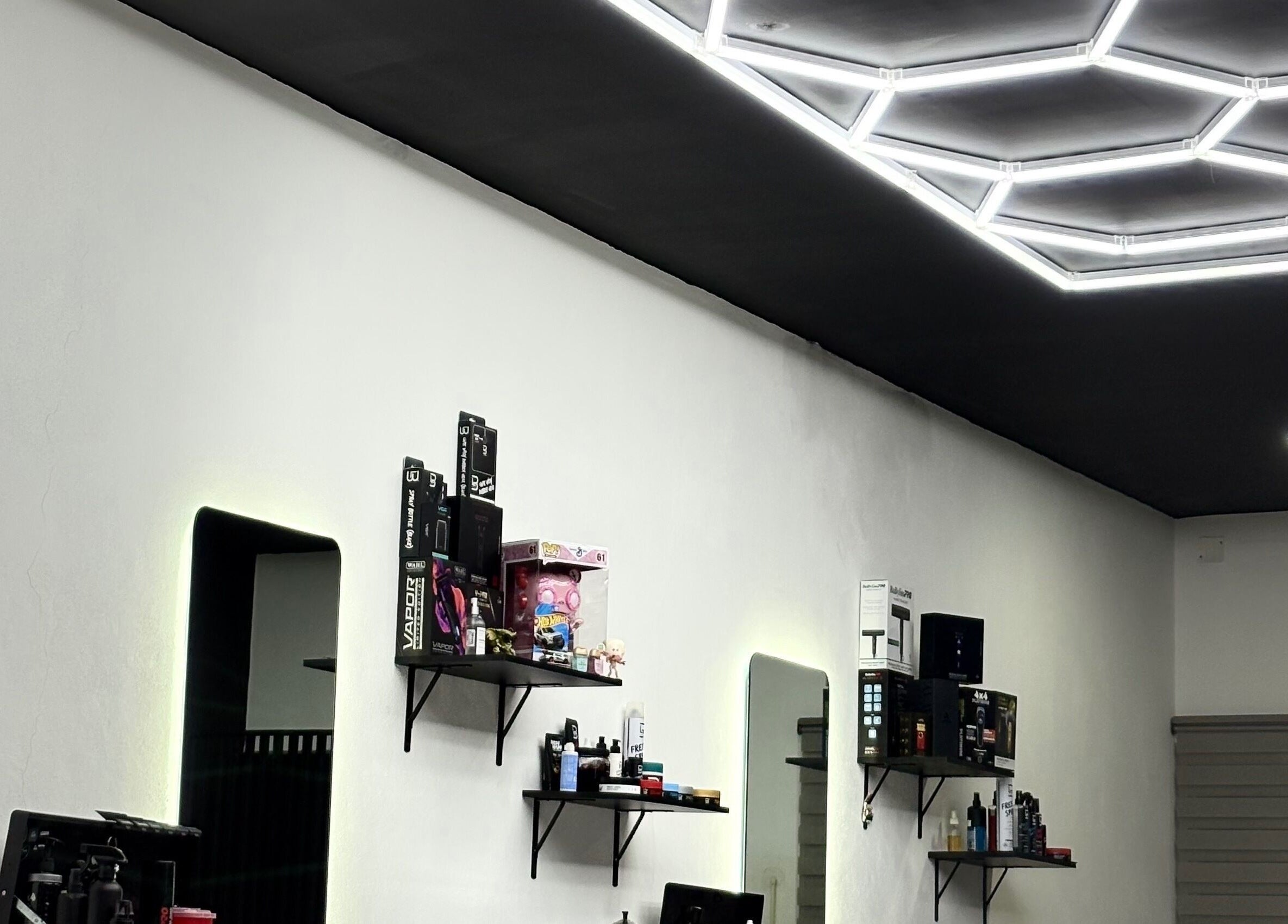 Interior de Fonsek Barber en Tepic, Nayarit, MX con luces y productos en estanterías.