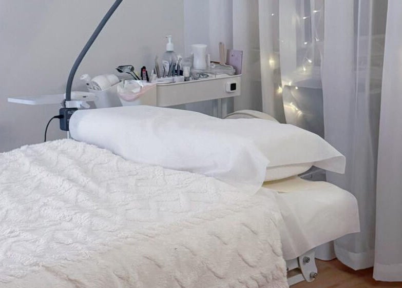 Luxurious spa bed setup at Jusjollie, Singapore with delicate fairy lights and plush linens.