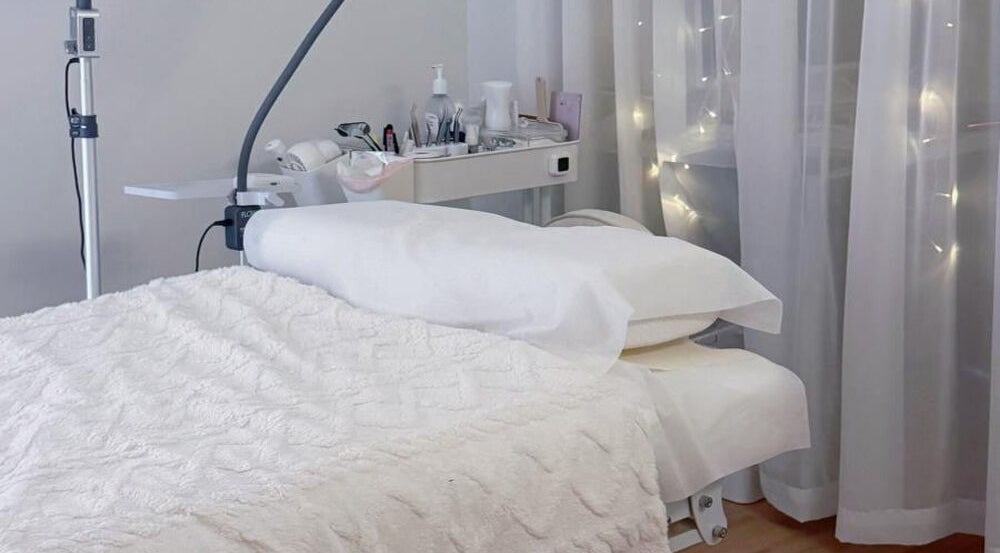 Luxurious spa bed setup at Jusjollie, Singapore with delicate fairy lights and plush linens.