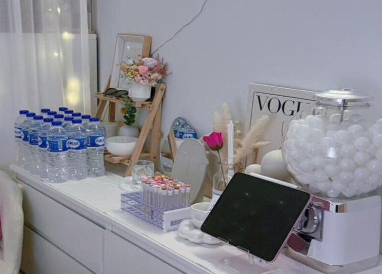 Aesthetic decor at Jusjollie, Singapore, SG includes water bottles, flowers, and a tablet in a chic setting.