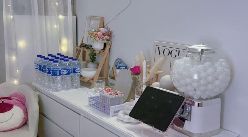 Aesthetic decor at Jusjollie, Singapore, SG includes water bottles, flowers, and a tablet in a chic setting.