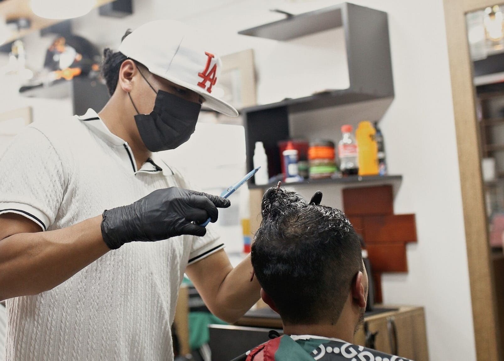 Barbero en D'Avila Barberia, Cuenca, Azuay, EC, recortando el cabello de un cliente con precisión.