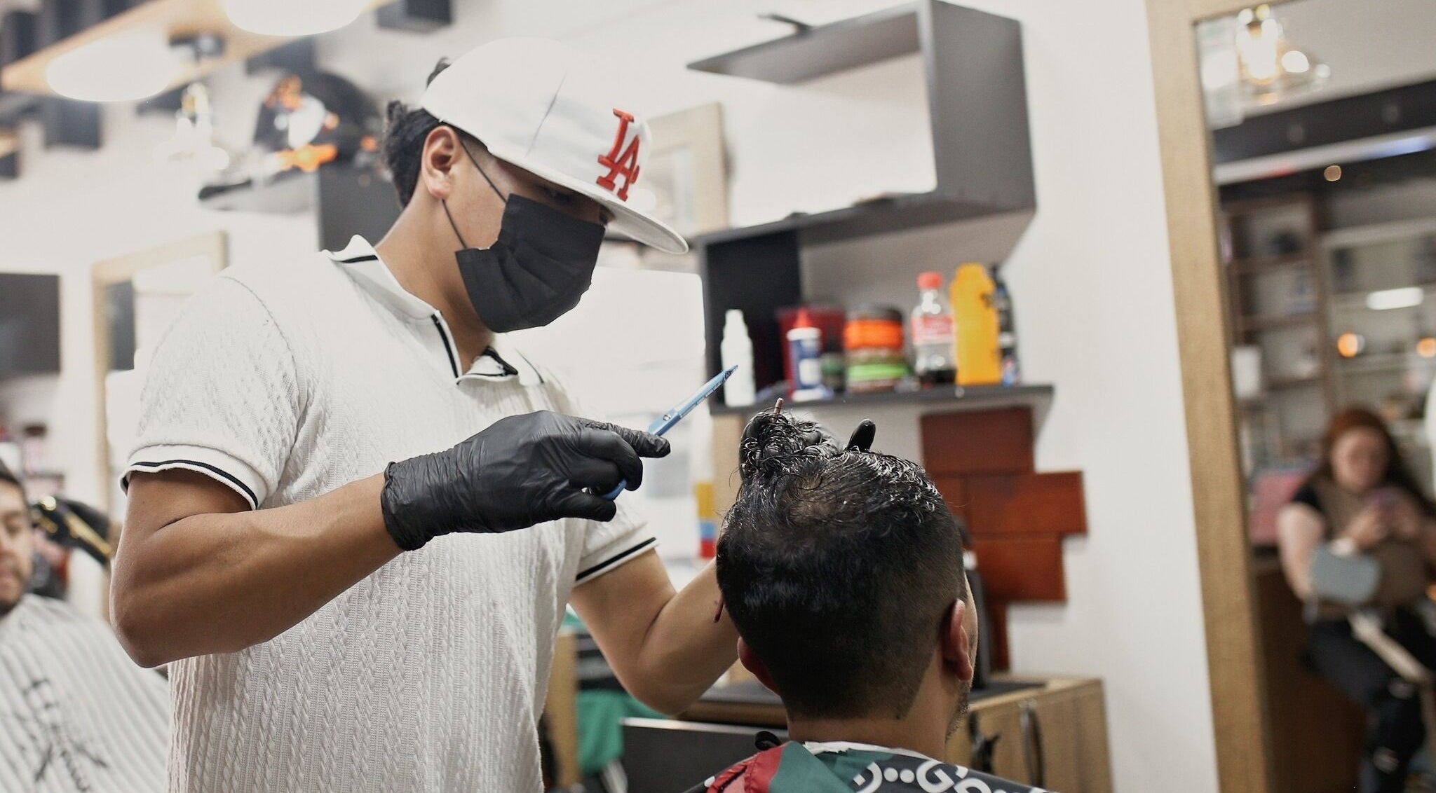 Barbero en D'Avila Barberia, Cuenca, Azuay, EC, recortando el cabello de un cliente con precisión.