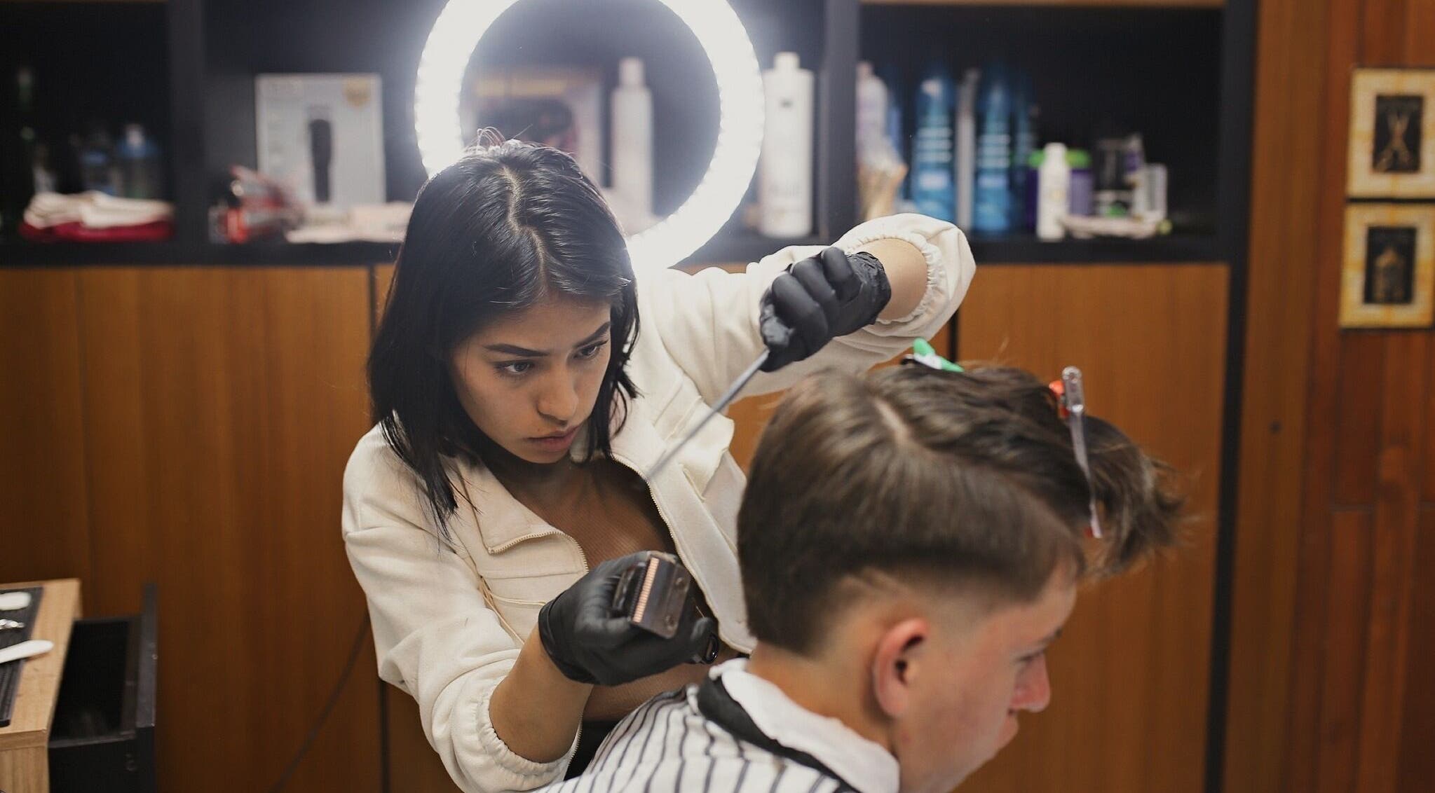 Estilista profesional haciendo un corte en D'Avila Barberia, Cuenca, Azuay, EC.