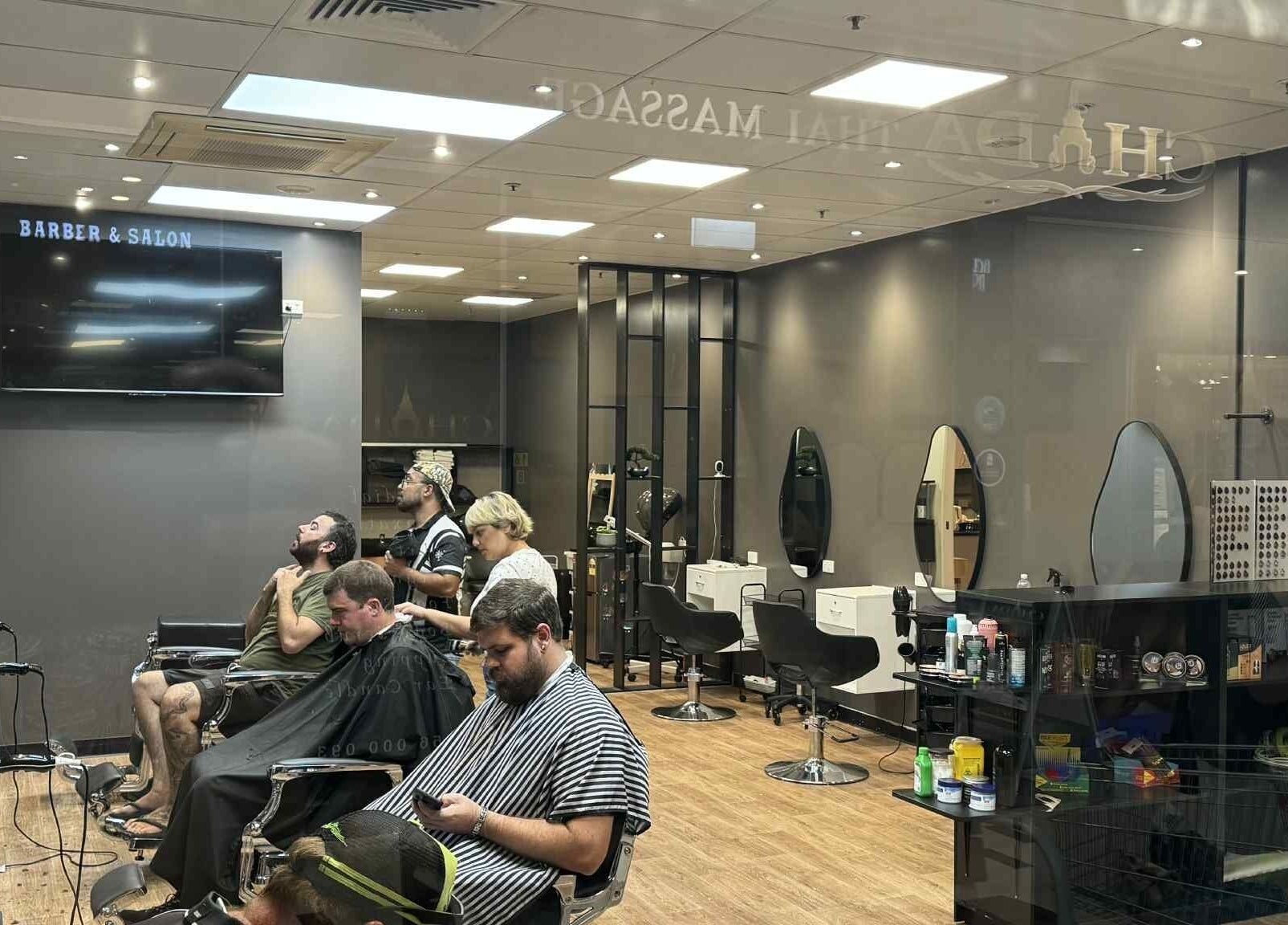 Interior of Captain Barber Oasis, a modern salon in Palmerston City, Northern Territory, AU, with clients and barbers.