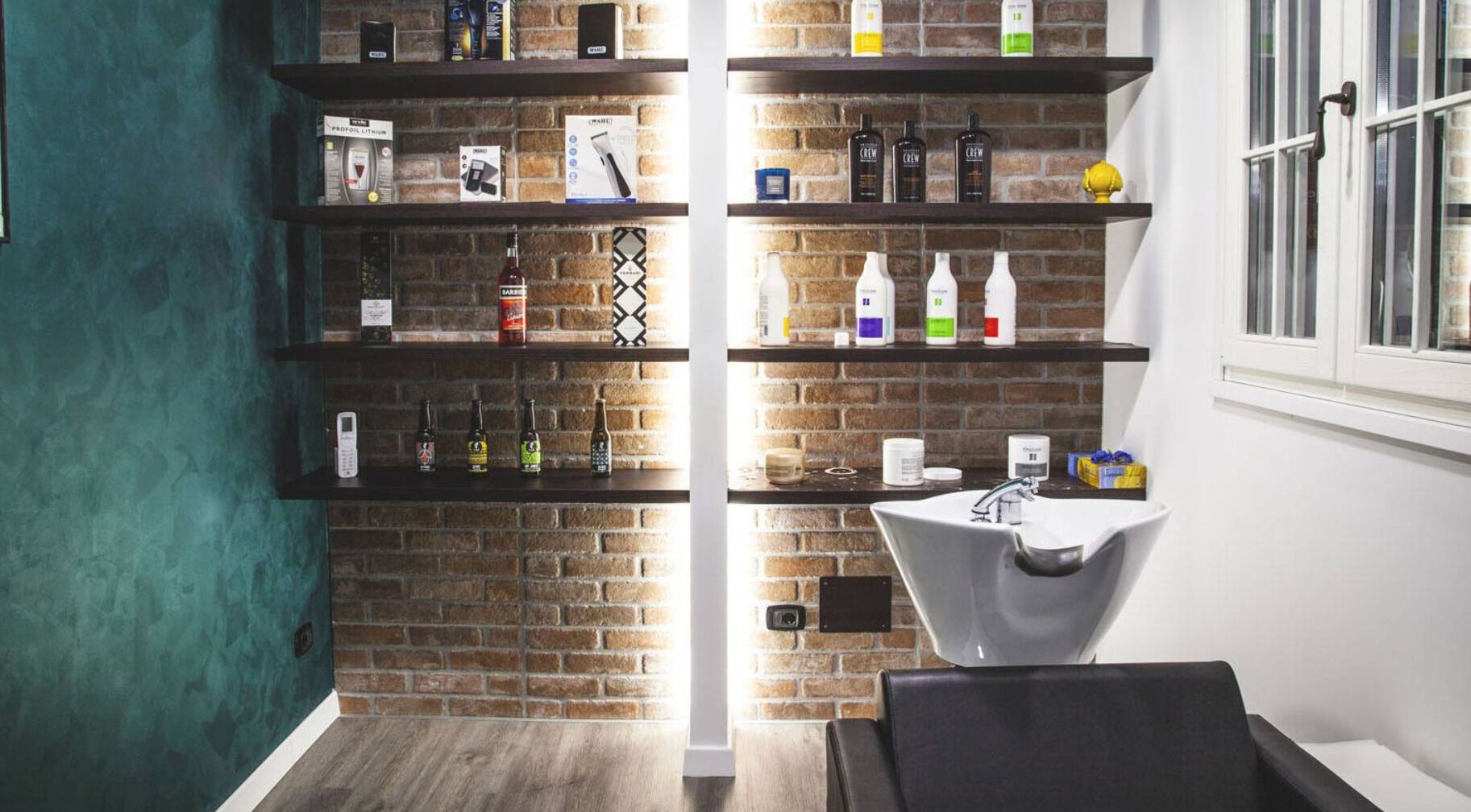 Scaffali prodotti e lavandino moderno presso From Zero Barberia Lucana, Matera, Basilicata, IT.