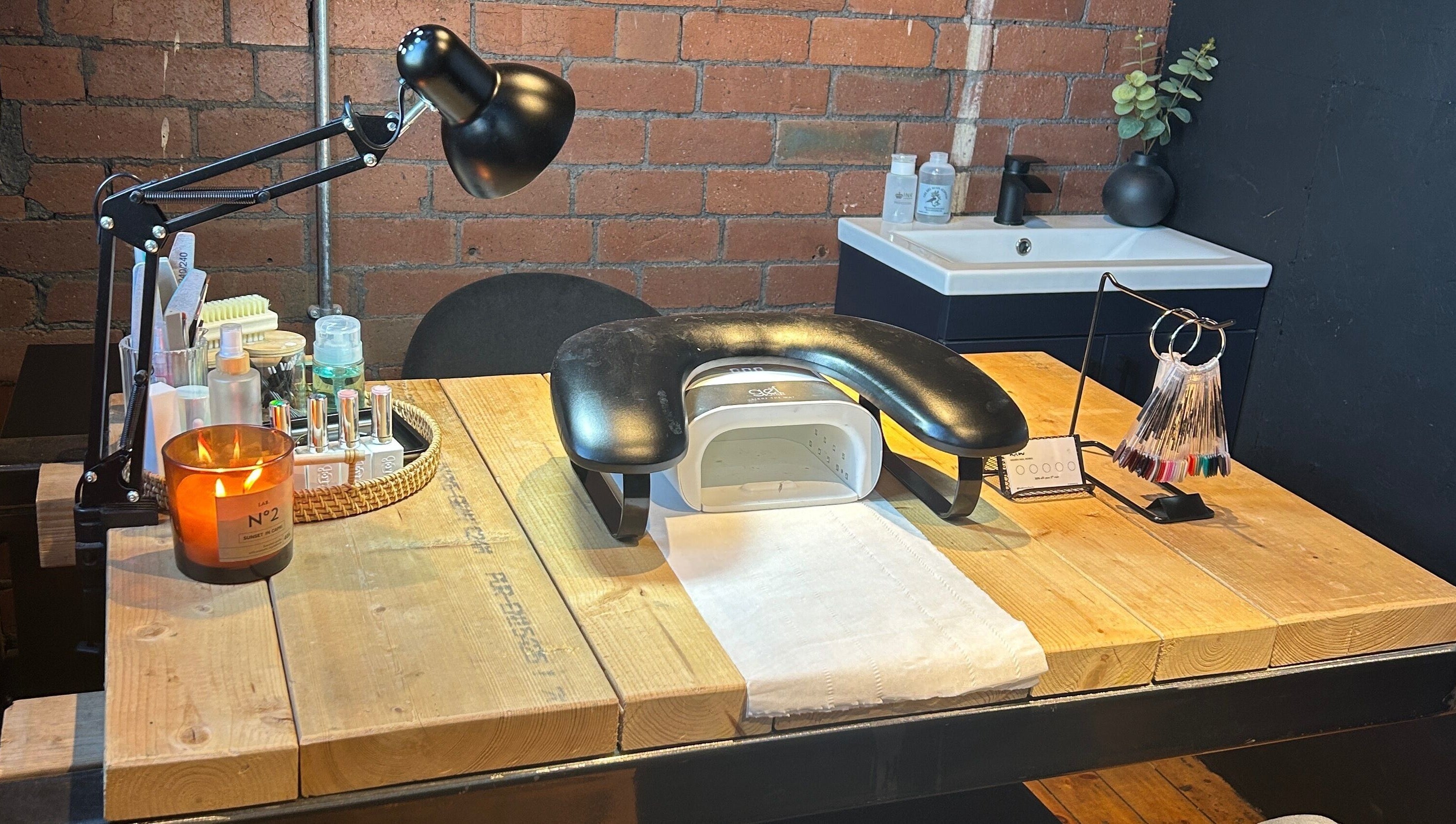 Modern nail station at Hidden Nail Works, Middlestown, England, GB with stylish lamp, nail tools, and cozy ambiance.