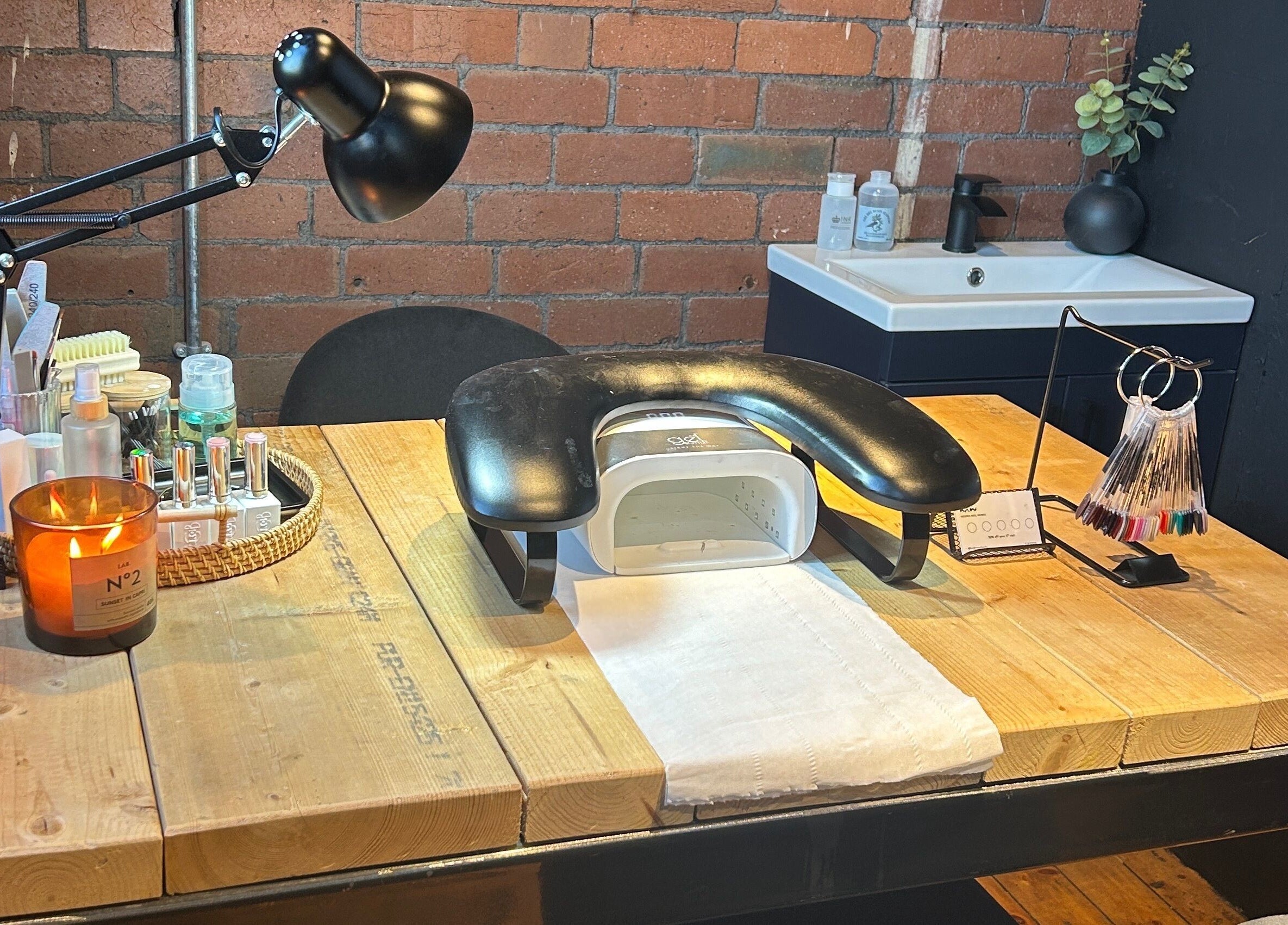 Modern nail station at Hidden Nail Works, Middlestown, England, GB with stylish lamp, nail tools, and cozy ambiance.