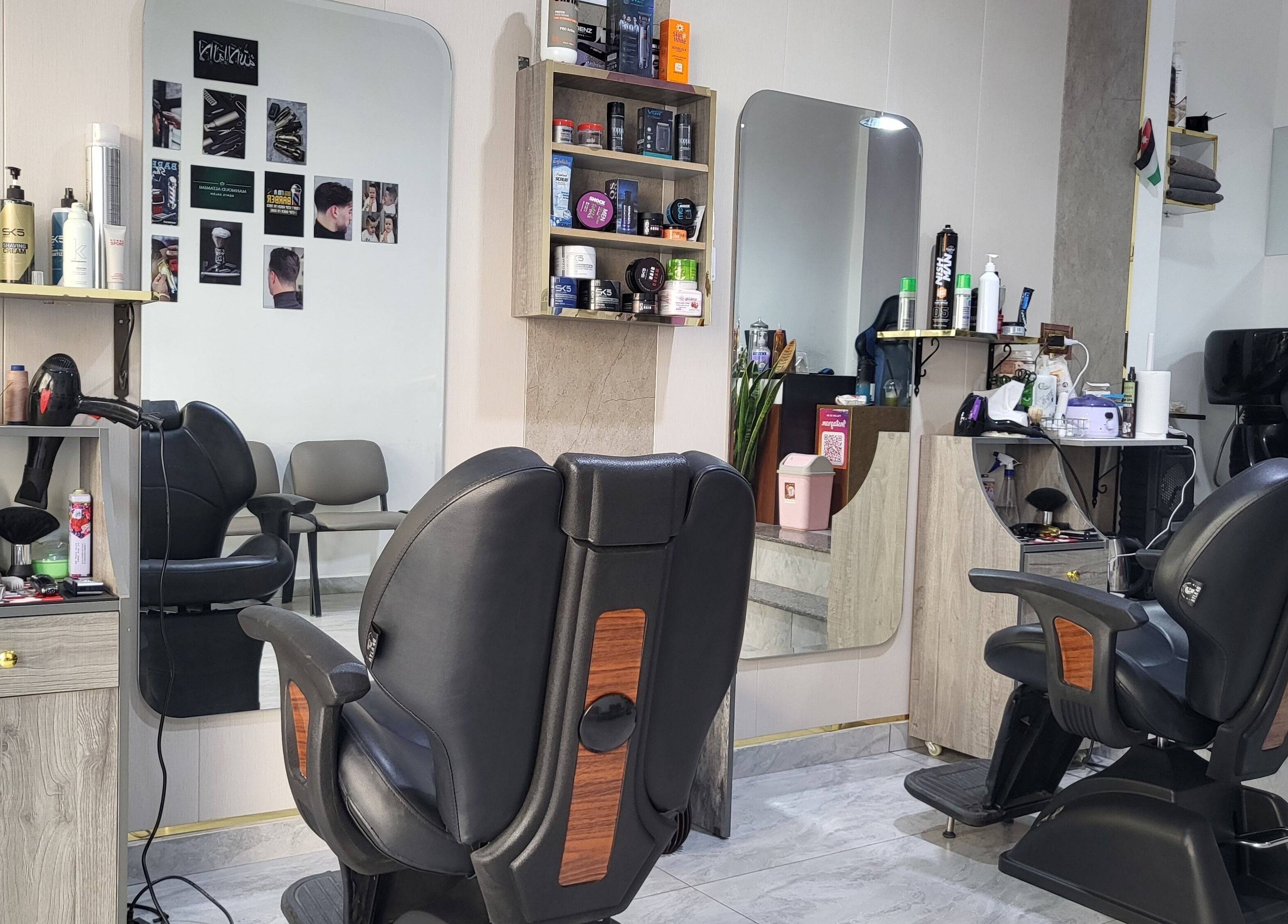 داخل محل حلاقة آلهامود في عمّان، محافظة العاصمة، JO مع كراسي ومرايا ومعدات حلاقة.