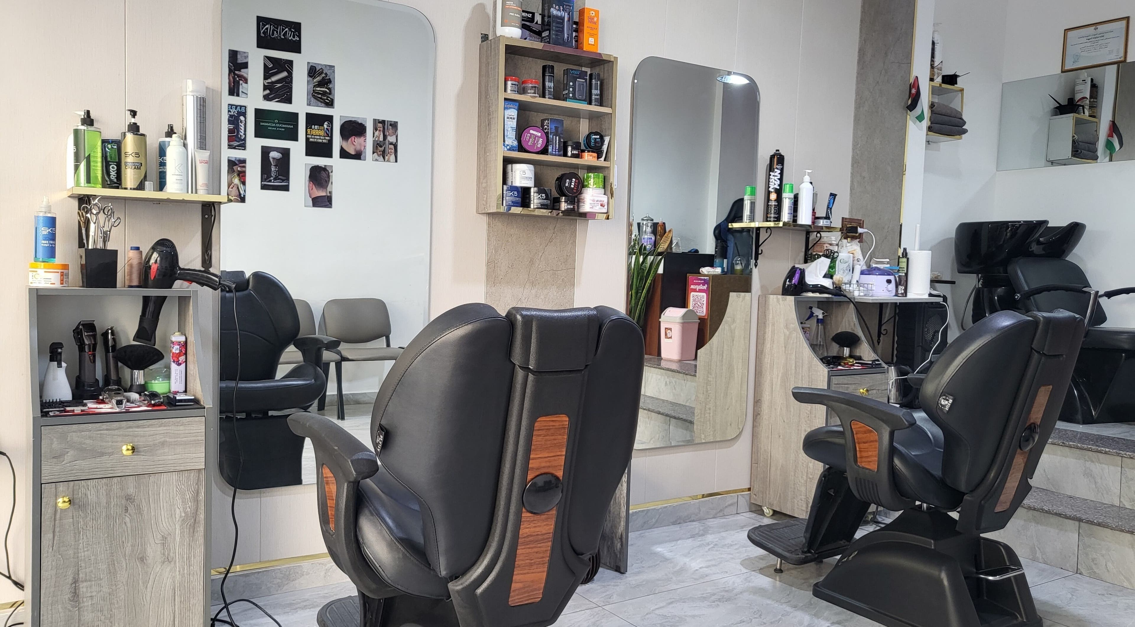 داخل محل حلاقة آلهامود في عمّان، محافظة العاصمة، JO مع كراسي ومرايا ومعدات حلاقة.