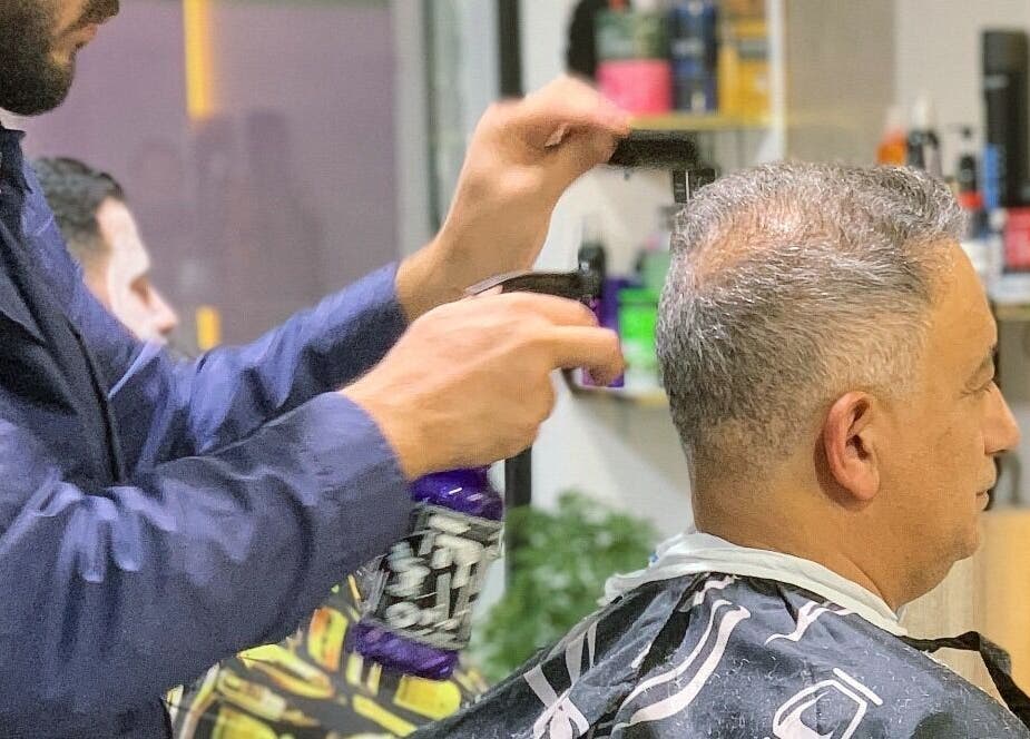 حلاق يعمل على تقديم خدمة قص شعر لعميل في محل الحلاقة Almahmoud barber shop, عمّان, محافظة العاصمة, JO.