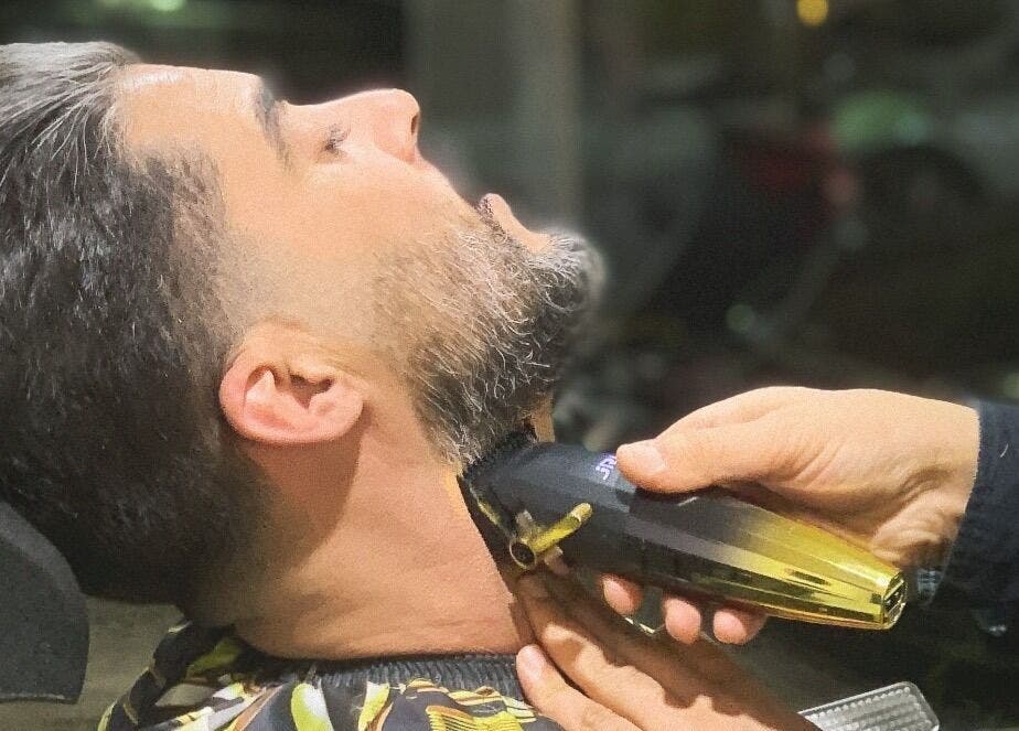 حلاق يستخدم آلة حلاقة لتحديد لحية رجل في محل الحلاقة Almahmoud barber shop, عمّان, محافظة العاصمة, JO.