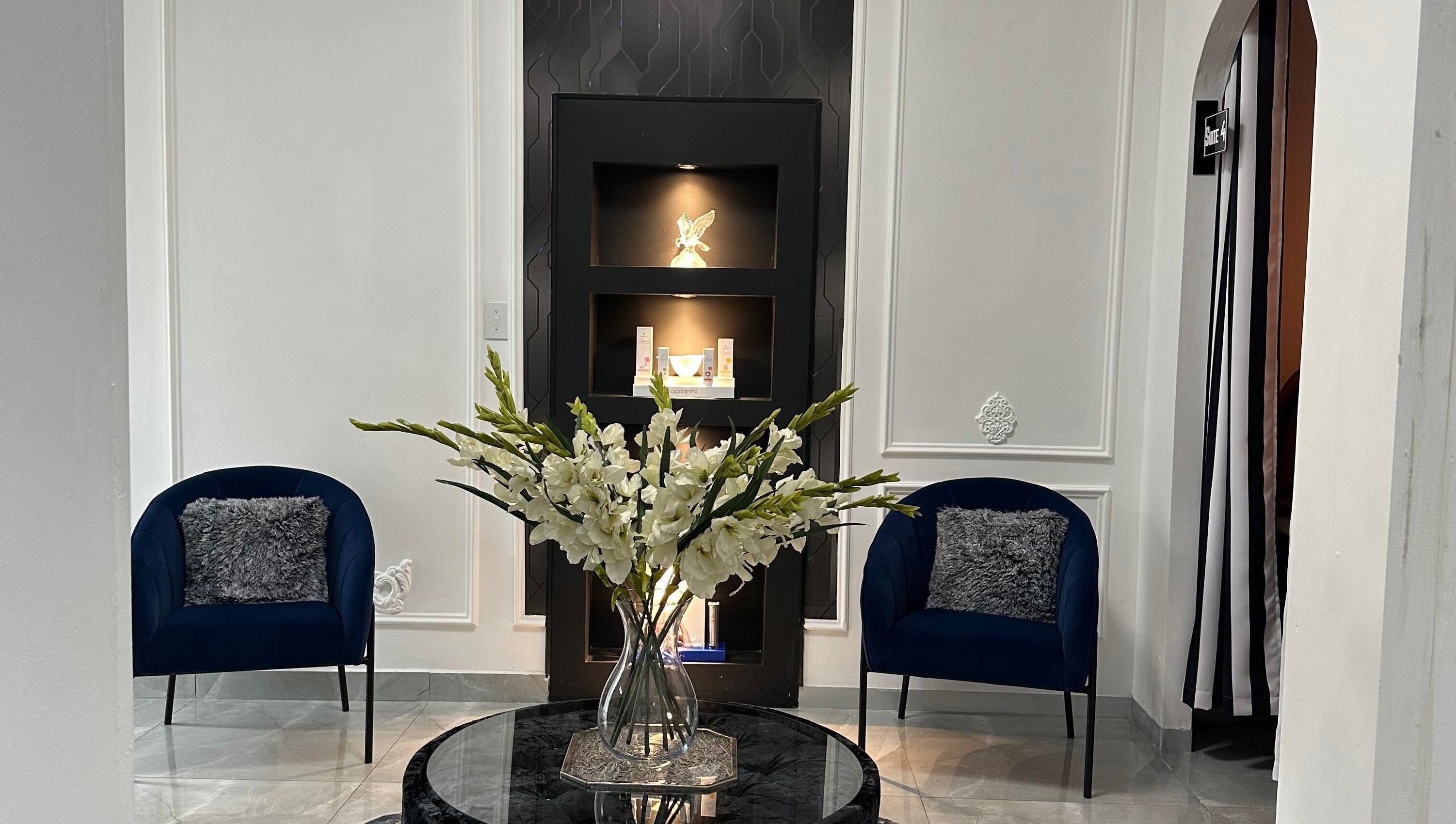 Sophisticated lounge at Eliora Aesthetic Clinic in Midrand, Gauteng, ZA with blue chairs and floral centerpiece.