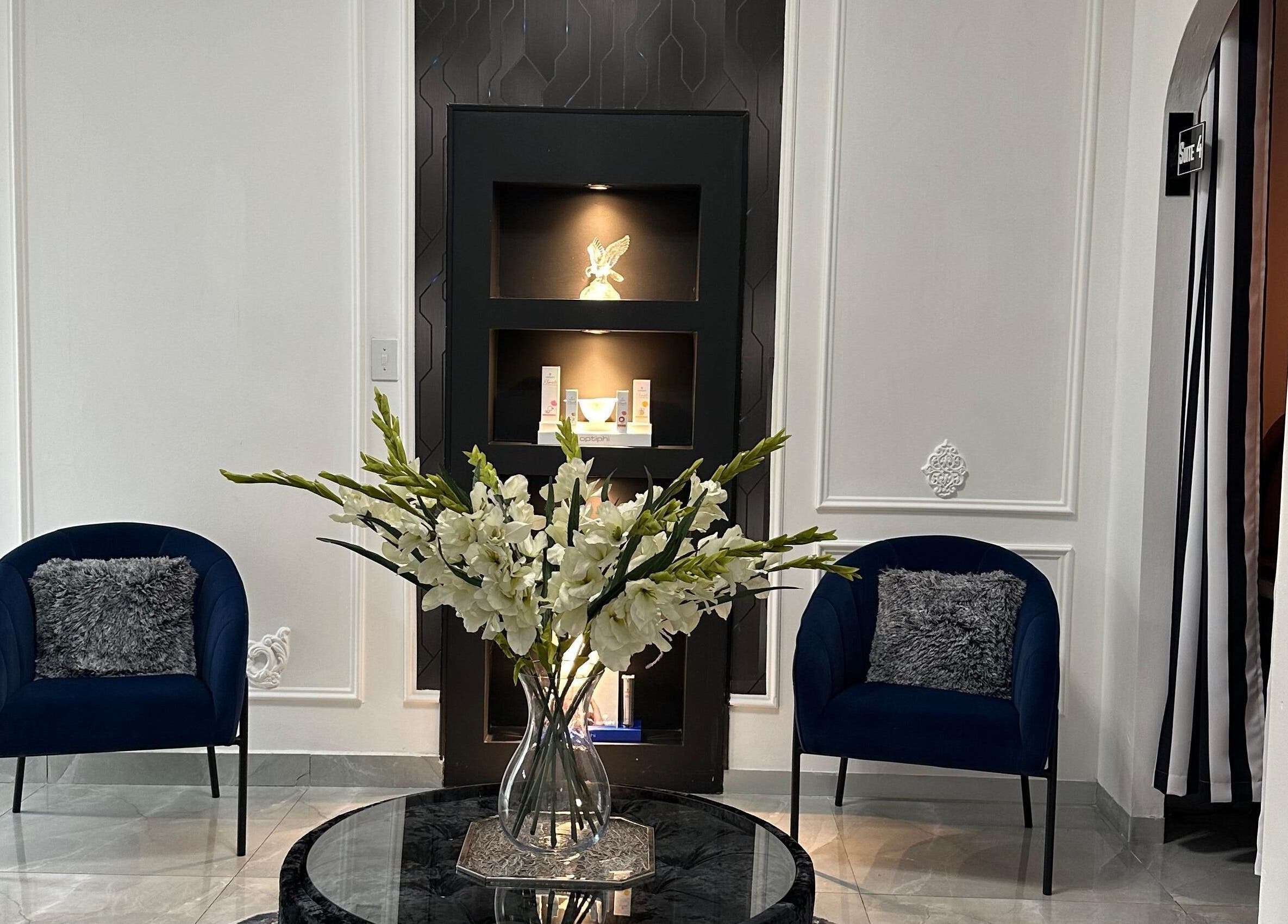 Sophisticated lounge at Eliora Aesthetic Clinic in Midrand, Gauteng, ZA with blue chairs and floral centerpiece.