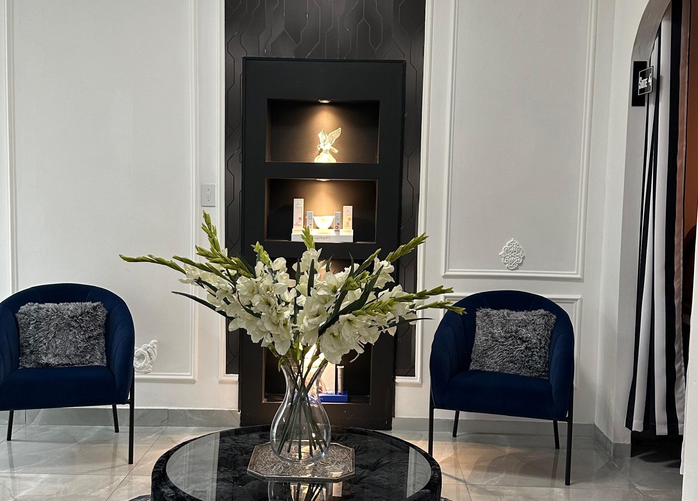 Sophisticated lounge at Eliora Aesthetic Clinic in Midrand, Gauteng, ZA with blue chairs and floral centerpiece.