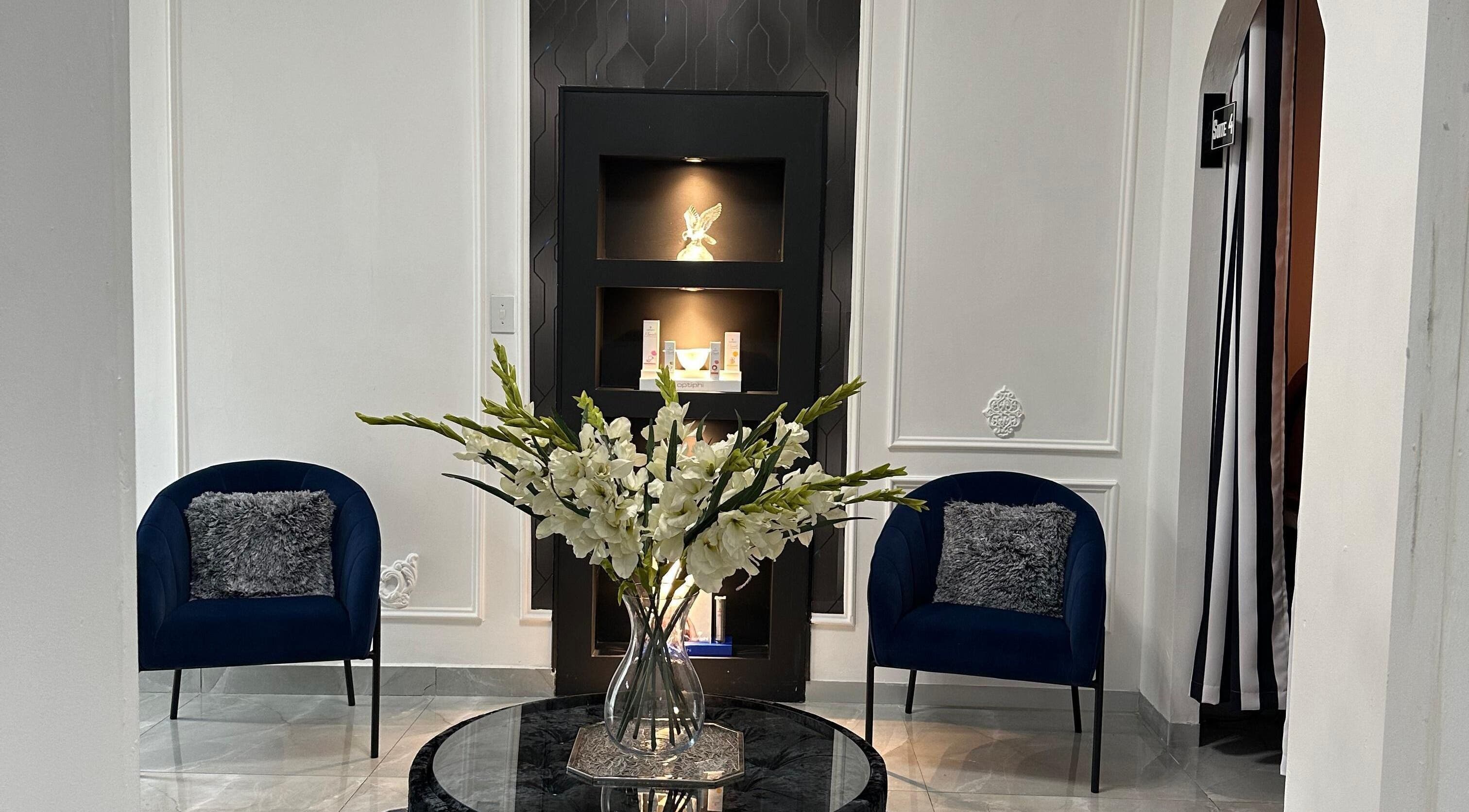 Sophisticated lounge at Eliora Aesthetic Clinic in Midrand, Gauteng, ZA with blue chairs and floral centerpiece.