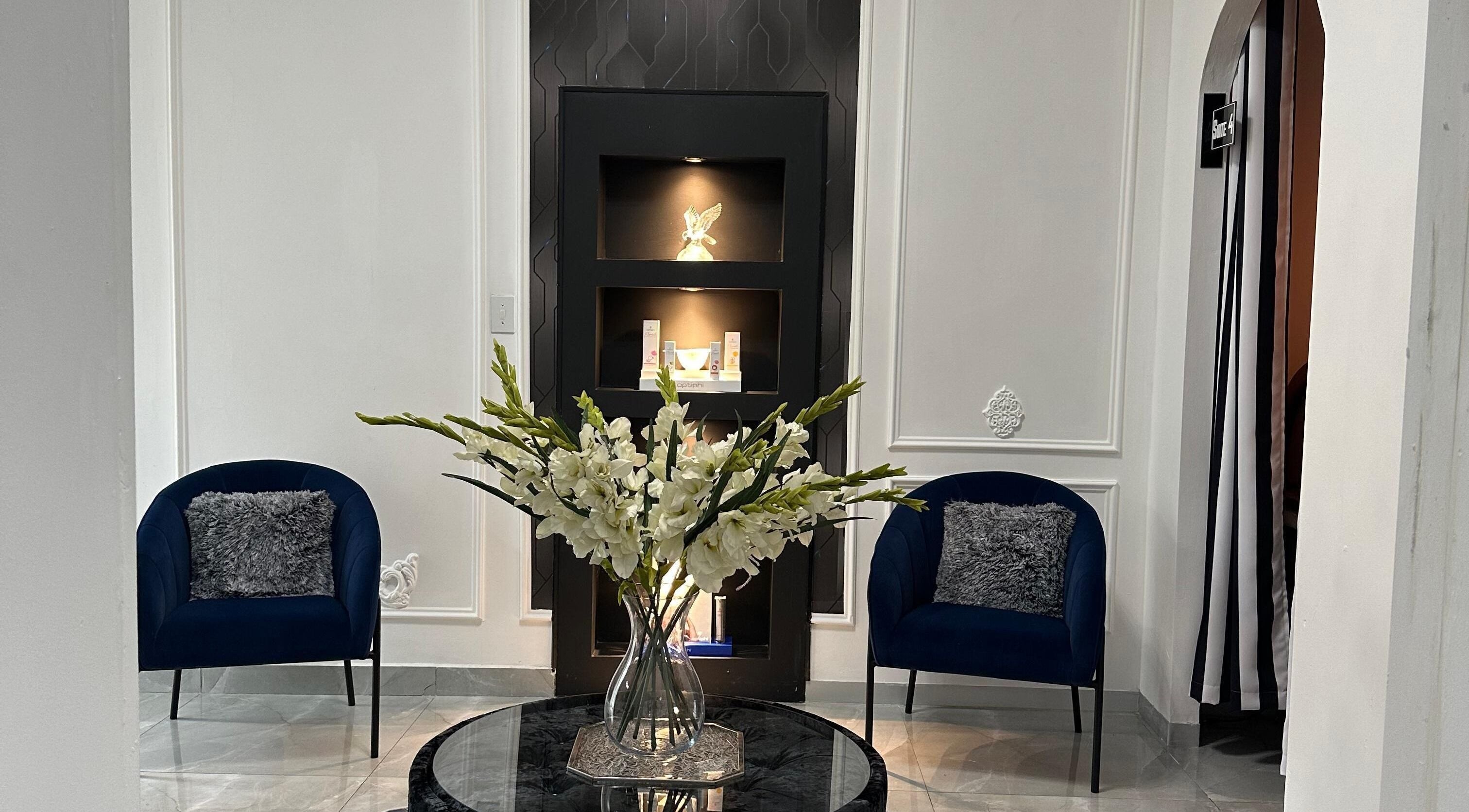 Sophisticated lounge at Eliora Aesthetic Clinic in Midrand, Gauteng, ZA with blue chairs and floral centerpiece.
