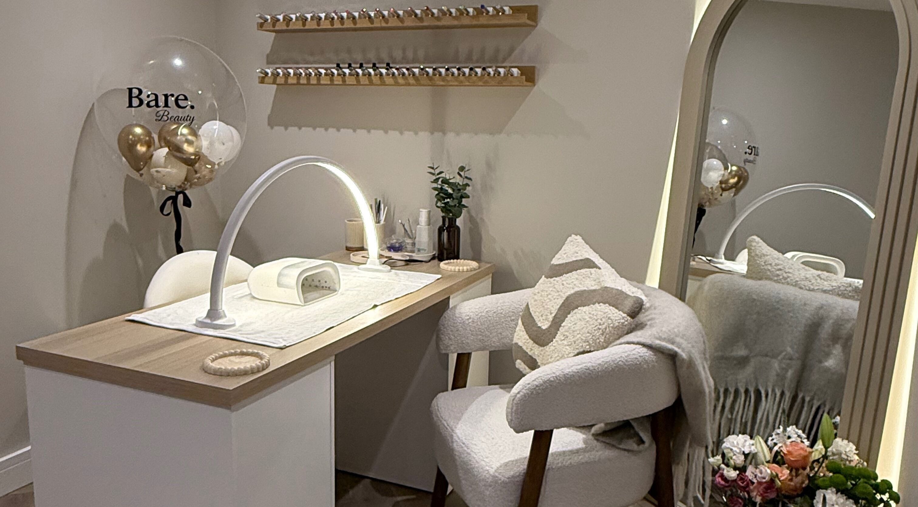 Elegant nail station at BARE Beauty, Birstall, England, GB, featuring cozy seating and nail polish display.