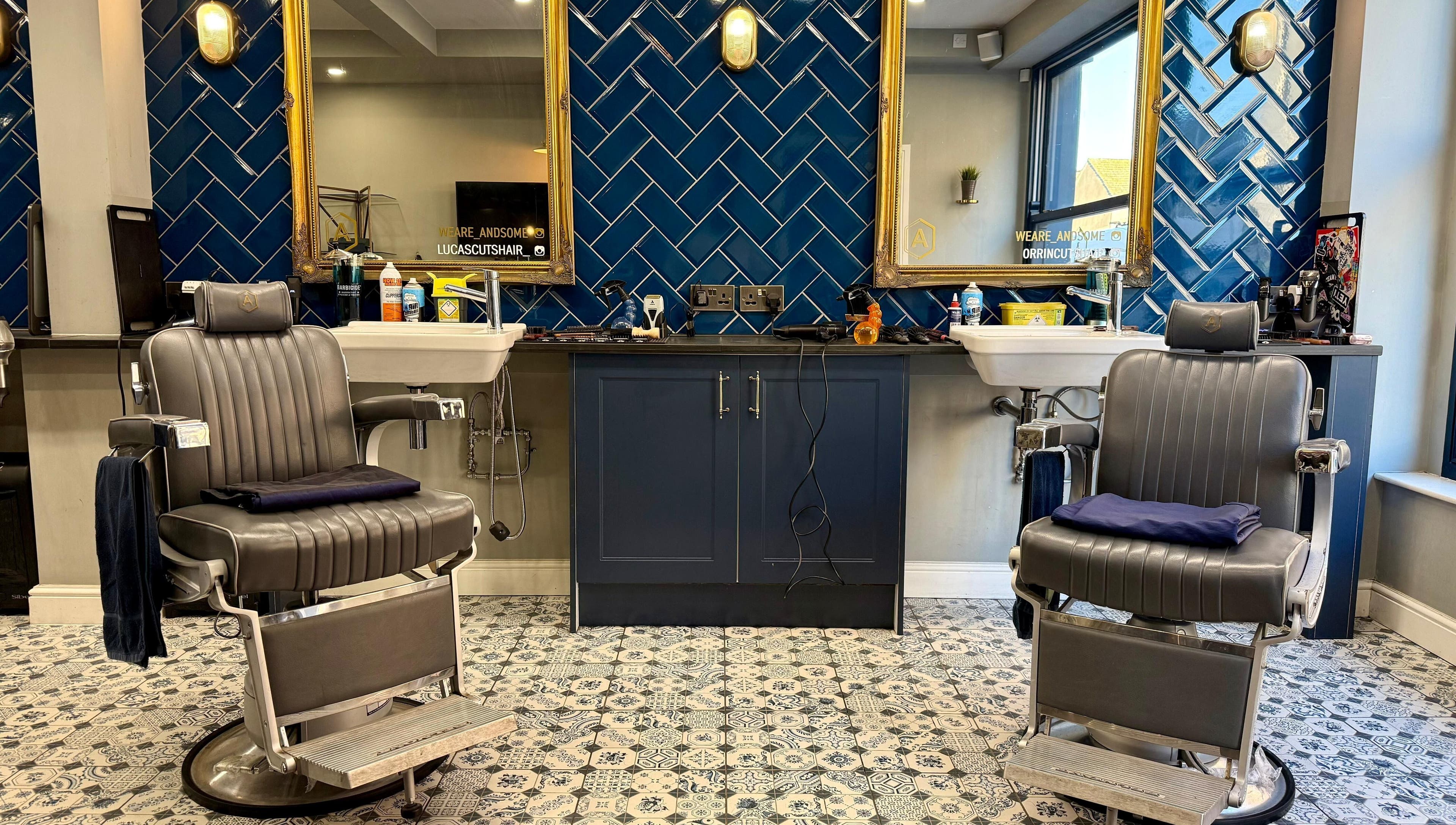 Modern barber chairs at Andsome, Blackpool, England, GB, with stylish tile and mirror backdrop.