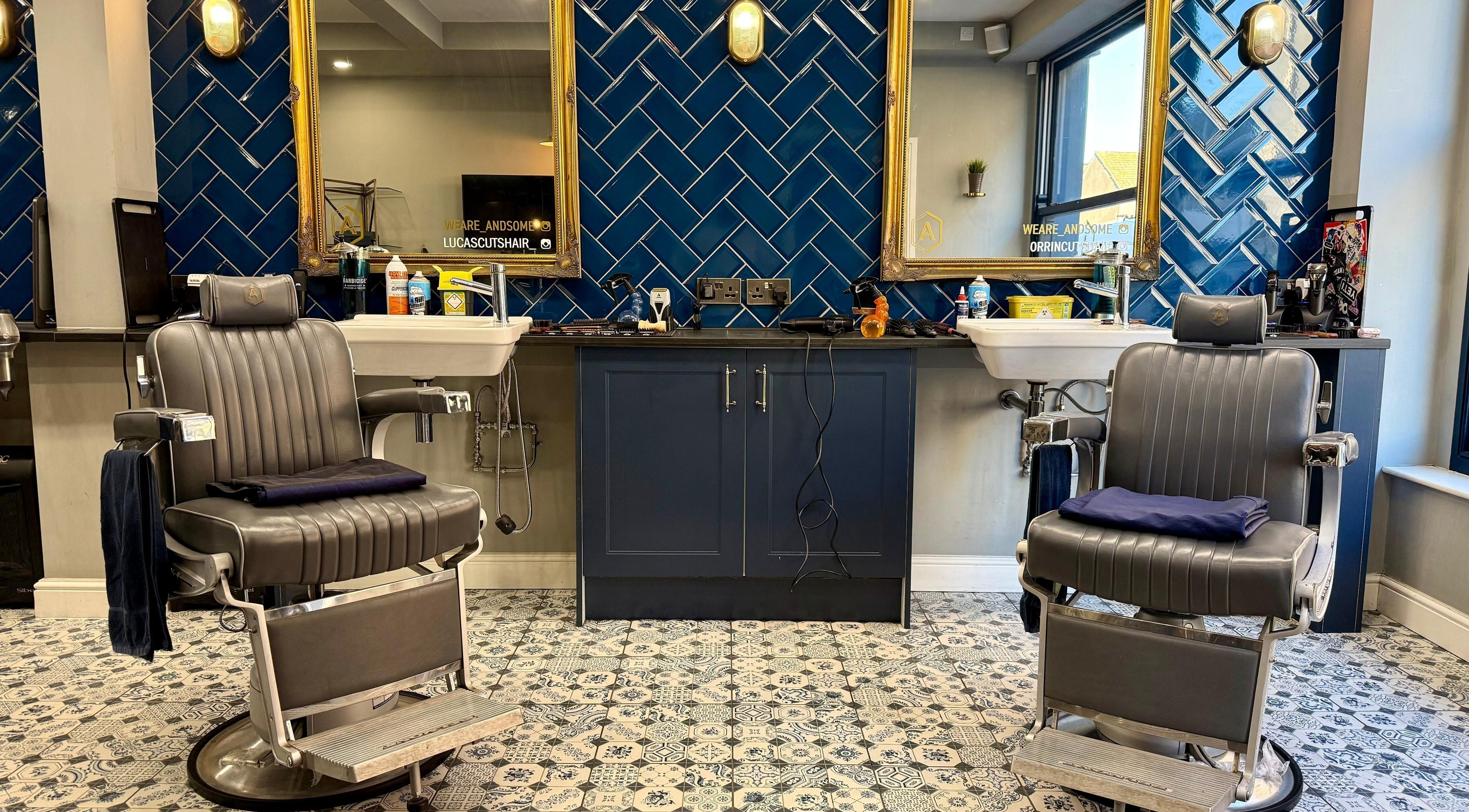 Modern barber chairs at Andsome, Blackpool, England, GB, with stylish tile and mirror backdrop.