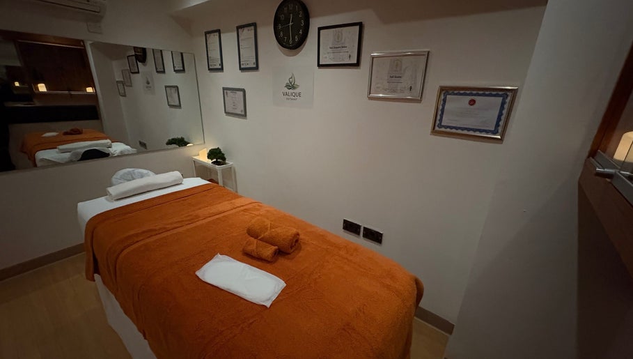 Serene massage room at Valique Retreat in Watford, England, GB with certificates and calming decor.