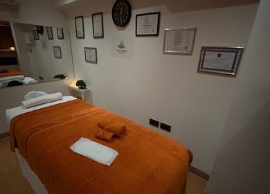 Serene massage room at Valique Retreat in Watford, England, GB with certificates and calming decor.