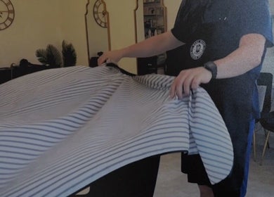 Staff setting up a barber chair at Redz Hedz Barbers, Goldthorpe, England, GB with striped cover.