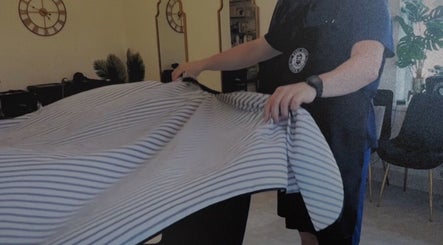 Staff setting up a barber chair at Redz Hedz Barbers, Goldthorpe, England, GB with striped cover.