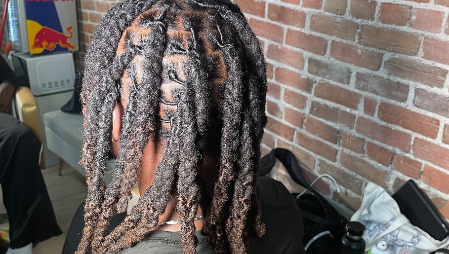 Tresses soignées chez Hairluxxury, Montréal, Québec, CA, offrant un style unique sur fond de mur en brique.