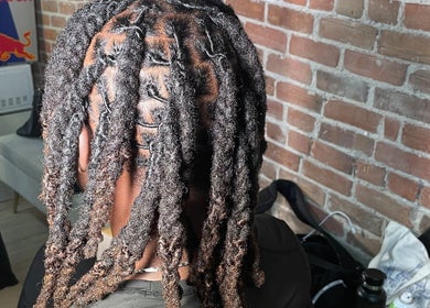 Tresses soignées chez Hairluxxury, Montréal, Québec, CA, offrant un style unique sur fond de mur en brique.