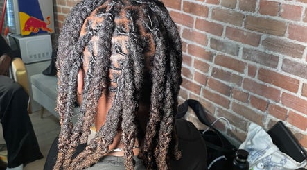 Tresses soignées chez Hairluxxury, Montréal, Québec, CA, offrant un style unique sur fond de mur en brique.