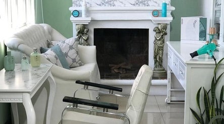 Interior elegante de VELVETWELLNESSCENTER en Quito, Pichincha, EC, con sillas blancas y chimenea decorativa.