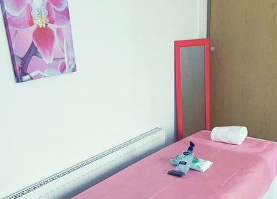Clean waxing room at Brazil Waxing Woodside Park, London, England, GB with pink decor and a massage table.