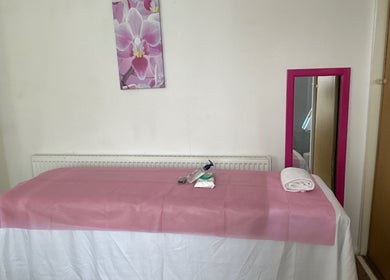 Calm waxing room at Brazil Waxing Woodside Park, London, England, GB with pink decor and massage table.