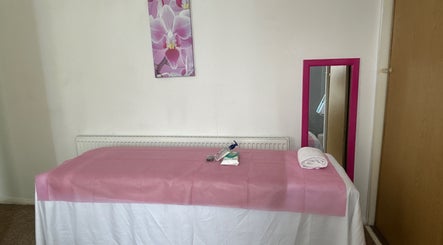 Calm waxing room at Brazil Waxing Woodside Park, London, England, GB with pink decor and massage table.