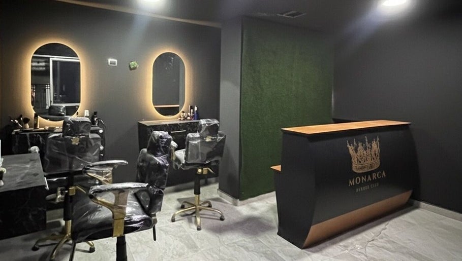 Interior elegante de Monarca Barber Club en Soledad, Atlántico, CO con sillas de peluquería y mostrador de recepción.