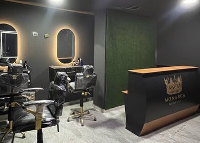 Interior elegante de Monarca Barber Club en Soledad, Atlántico, CO con sillas de peluquería y mostrador de recepción.