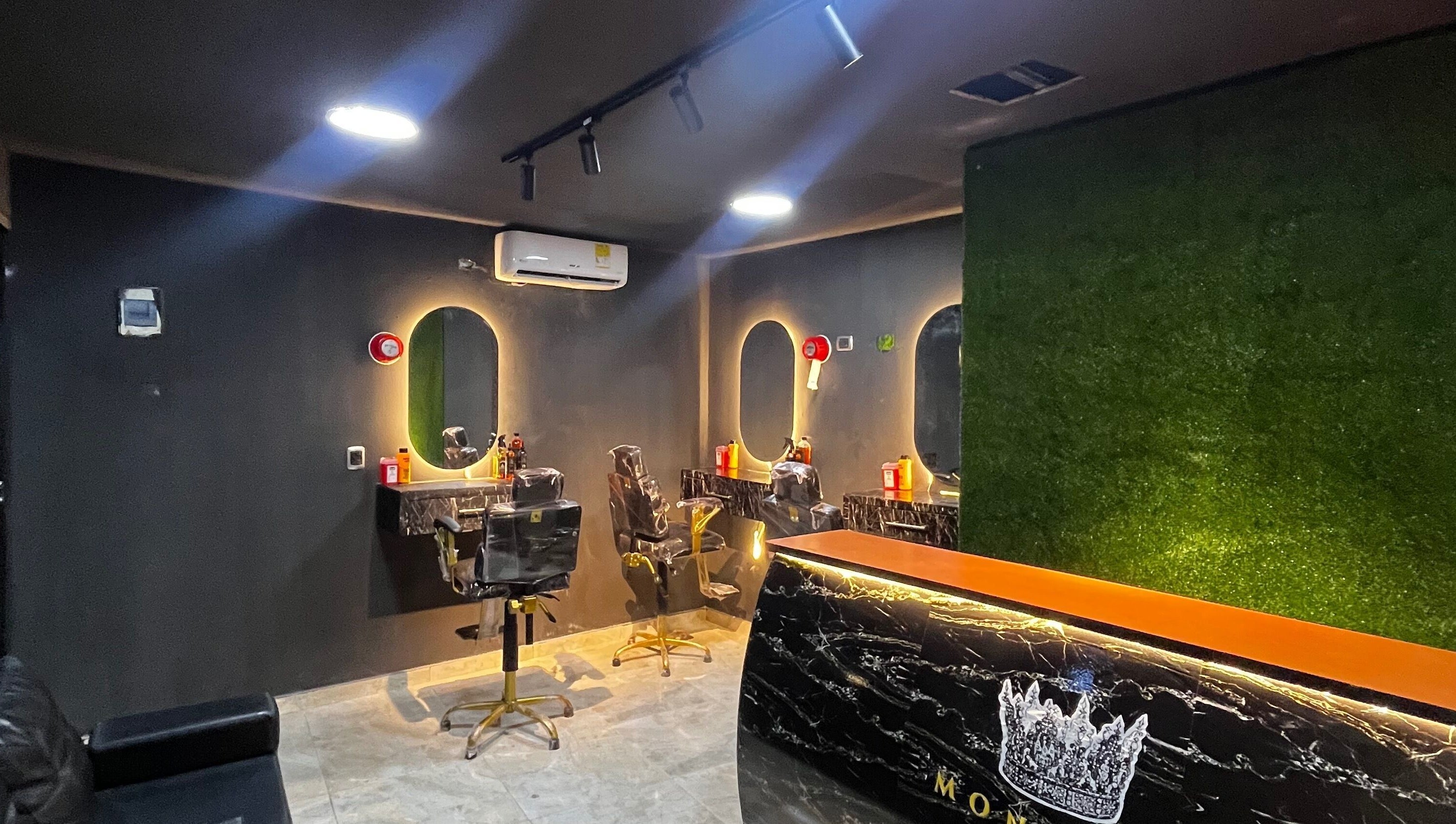 Interior moderno de Monarca Barber Club, Soledad, Atlántico, CO, con espejos iluminados y sillas de barbero.