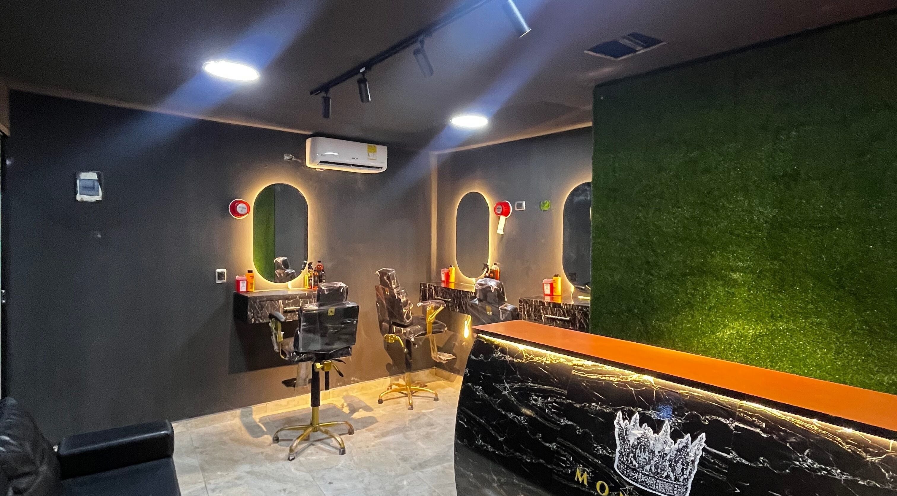 Interior moderno de Monarca Barber Club, Soledad, Atlántico, CO, con espejos iluminados y sillas de barbero.