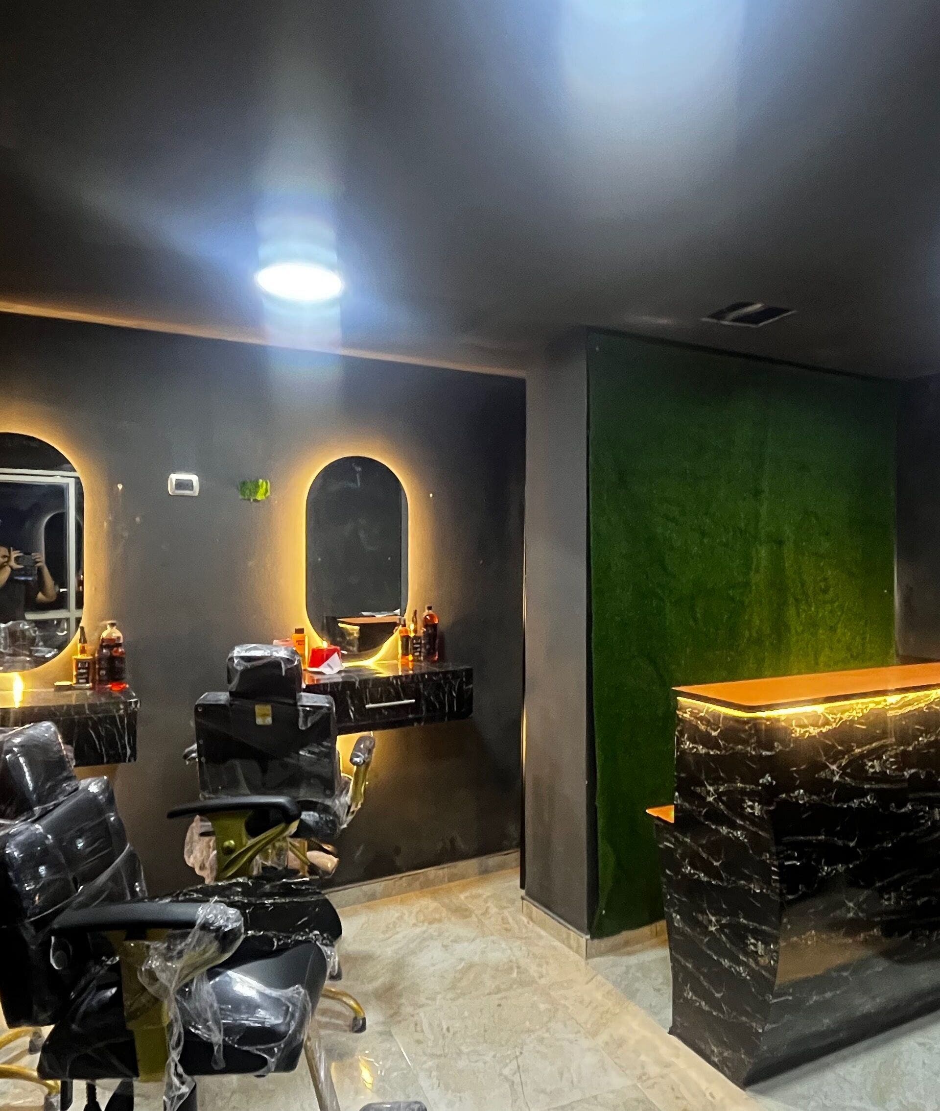 Interior elegante de Monarca Barber Club, Soledad, Atlántico, CO, mostrando sillas modernas y espejo iluminado.