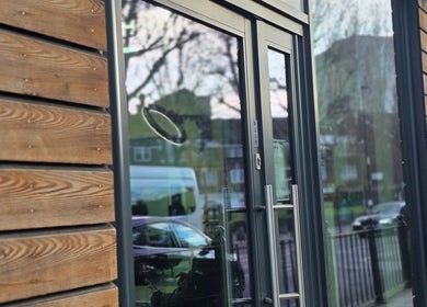 Modern glass entrance of Noor Blends, London, England, GB, with sleek wooden siding.