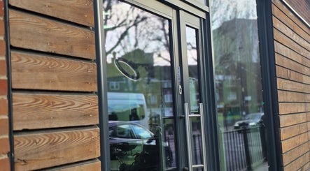 Modern glass entrance of Noor Blends, London, England, GB, with sleek wooden siding.