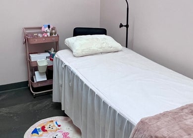 Cozy treatment room at I Lash & Art, Monrovia, California, US, featuring a bed and a cart with beauty supplies.