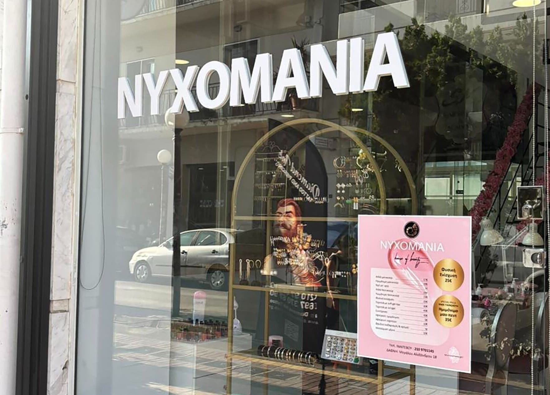 Η είσοδος του Νυχομανια Δάφνης στην Δάφνη Αττικής, GR με βιτρίνα και πινακίδα καταστήματος.