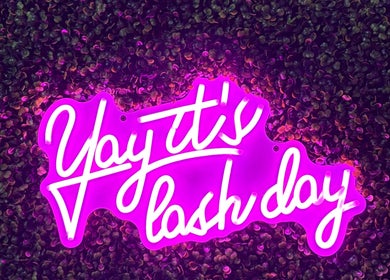 Vibrant neon sign at Nails by Paige in Payson, Arizona, US, showcasing 'Yay! It's lash day' text on leafy background.